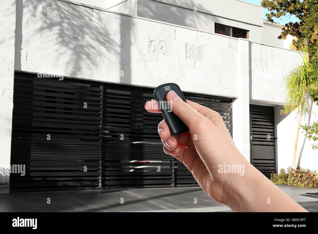 Woman using remote to control roller shutters outdoors, closeup Stock Photo