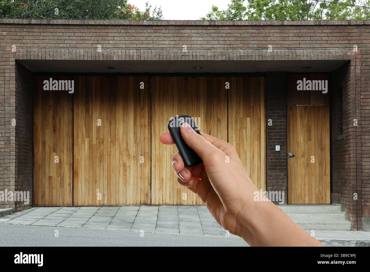 Woman using remote to control electric gate outdoors, closeup Stock Photo