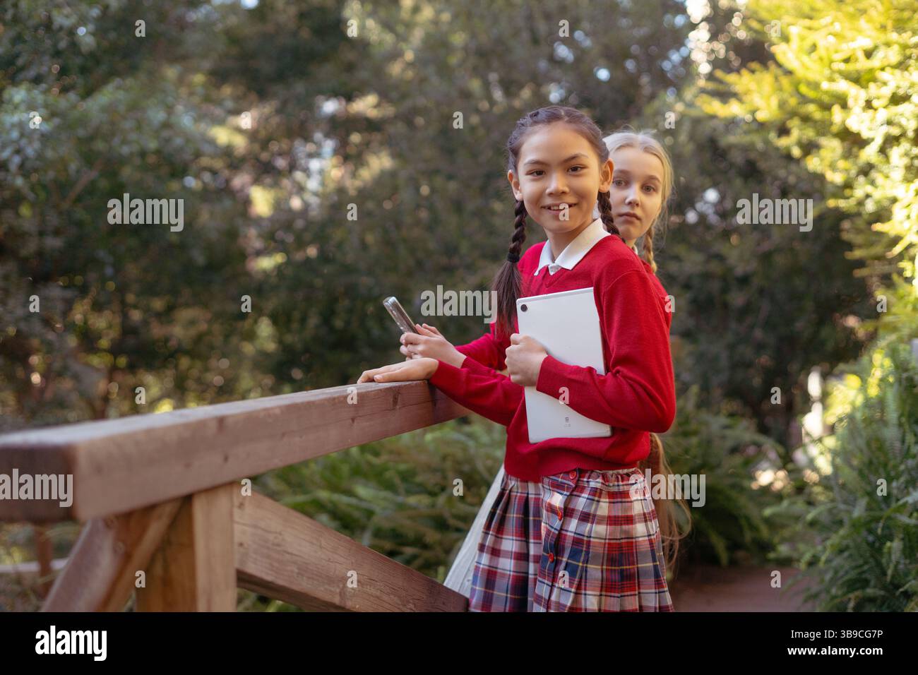 Elementary school students using tablet and smartphone in a park Stock Photo