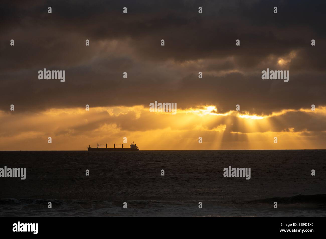 Freight Ship on the Water at Sunset with Light Rays Stock Photo