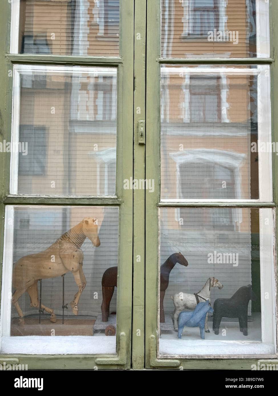 Vintage Wooden Horses in Antique Window with Reflected Facade, Stockholm, Sweden - Smartphone Captured Stock Image