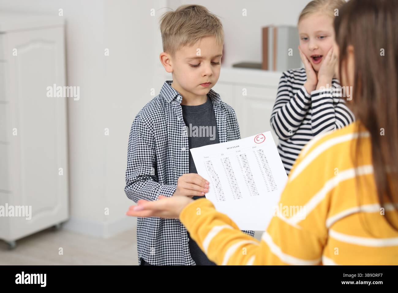 School grade. Sad boy showing answer sheet with bad mark to his mother ...