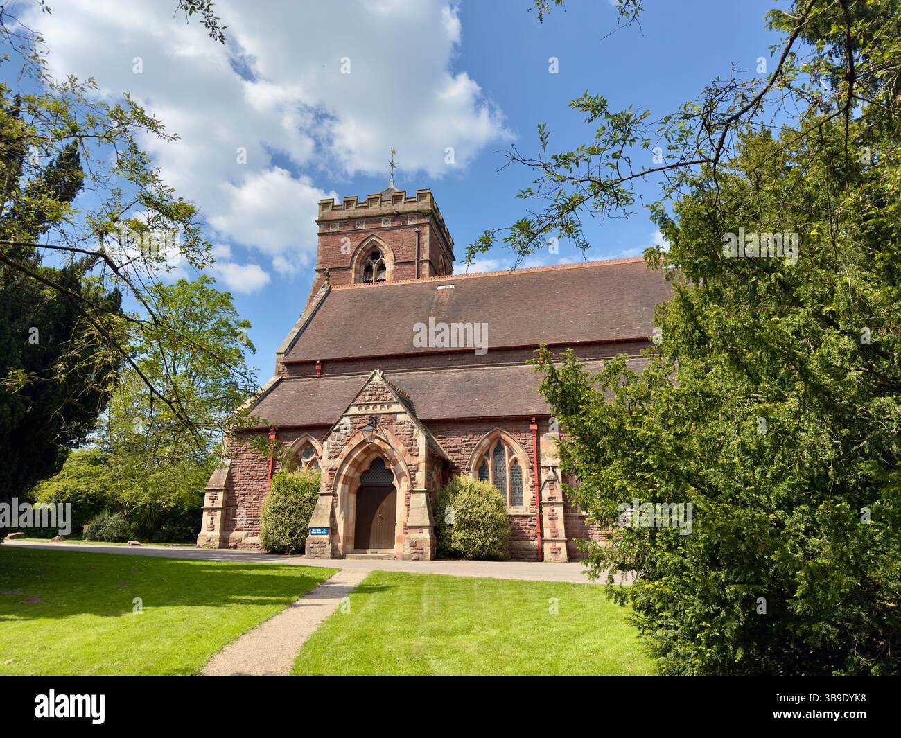 Sandstone church surrounded by trees on a sunny spring day. Holy Trinity Meole Brace, Shrewsbury in a well kept church yard. - Smartphone Captured Stock Image