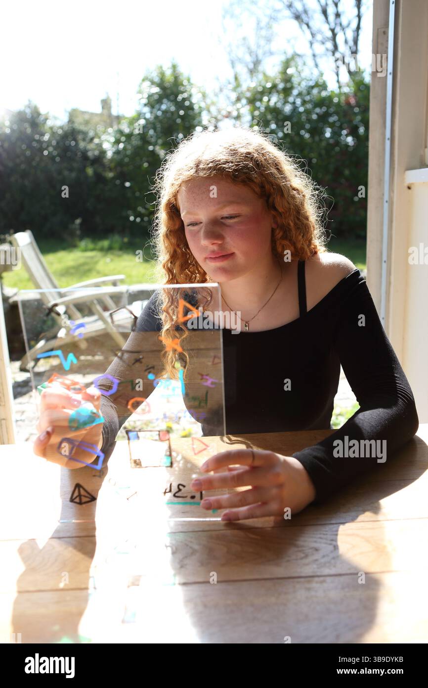 Teenage girl writing drawing maths symbols and shapes on tranparent ...