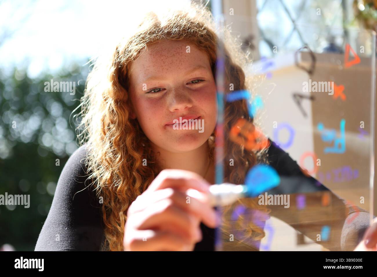 Teenage girl writing drawing maths symbols and shapes on tranparent ...