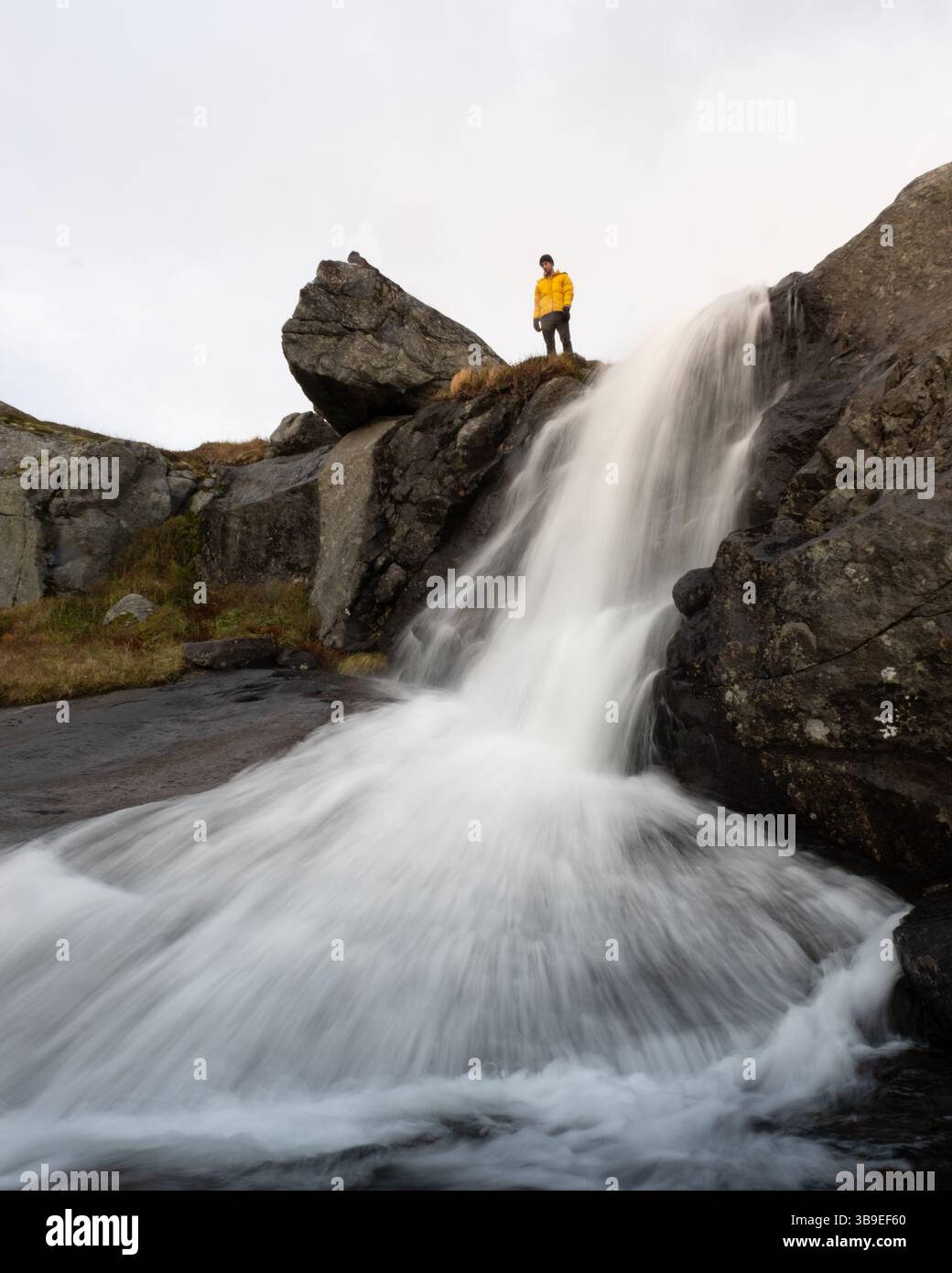 man-standing-near-waterfall-on-veinestinden-hiking-trail-in-lofoten