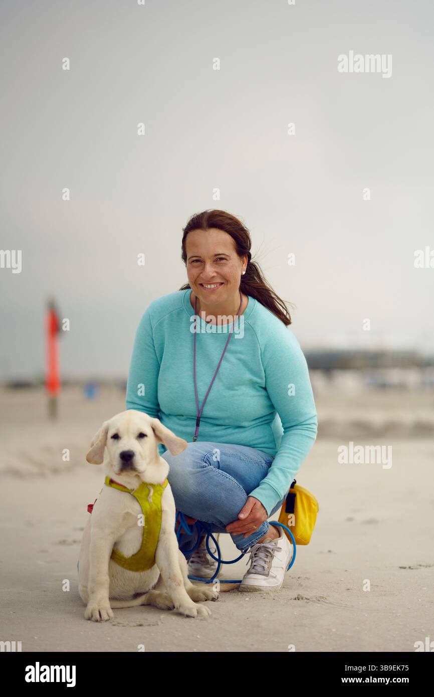 Attractive smiling woman posing with her puppy on the beach Stock Photo