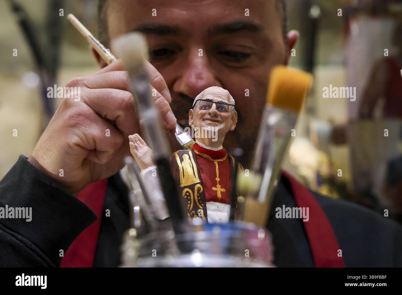 Naples, Italy. 09th May, 2025. Craftsman Gennaro Di Virgilio paints the finishing touches of a statue of newly elected Pope Leo XIV at his shop in San Gregorio Armeno Alley, a street where craftsmen of traditional Napolitan Christmas Crib figurines have workshops. Credit: Independent Photo Agency/Alamy Live News Stock Photo