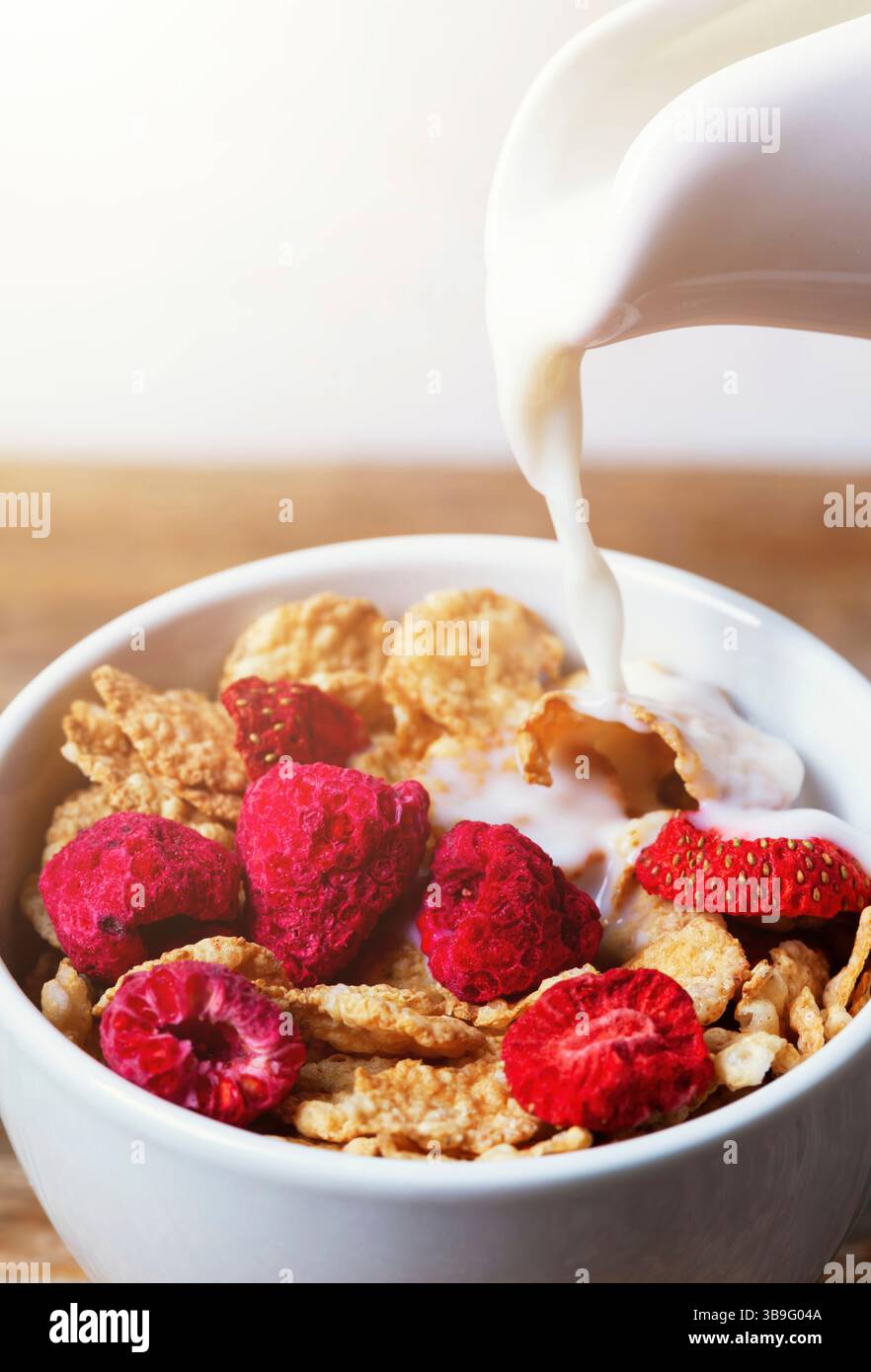 Pouring creamy milk into a white bowl filled with crunchy cereal ...