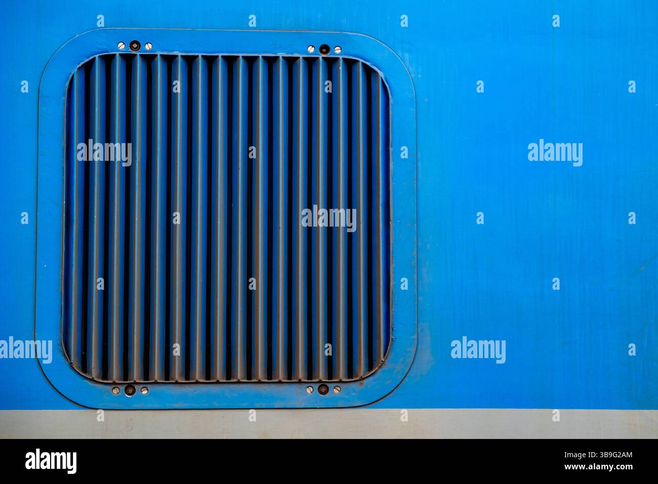 a square ventilation grille on a blue metal surface Stock Photo