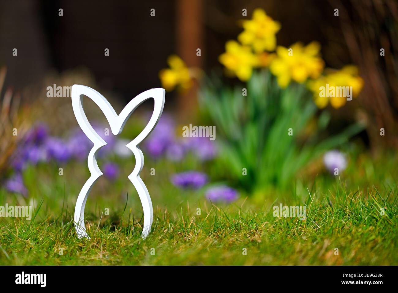 Easter bunny figure in front of spring flowers Stock Photo
