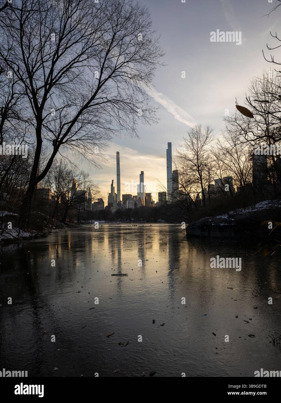 A serene winter landscape portraying a partially frozen lake ...