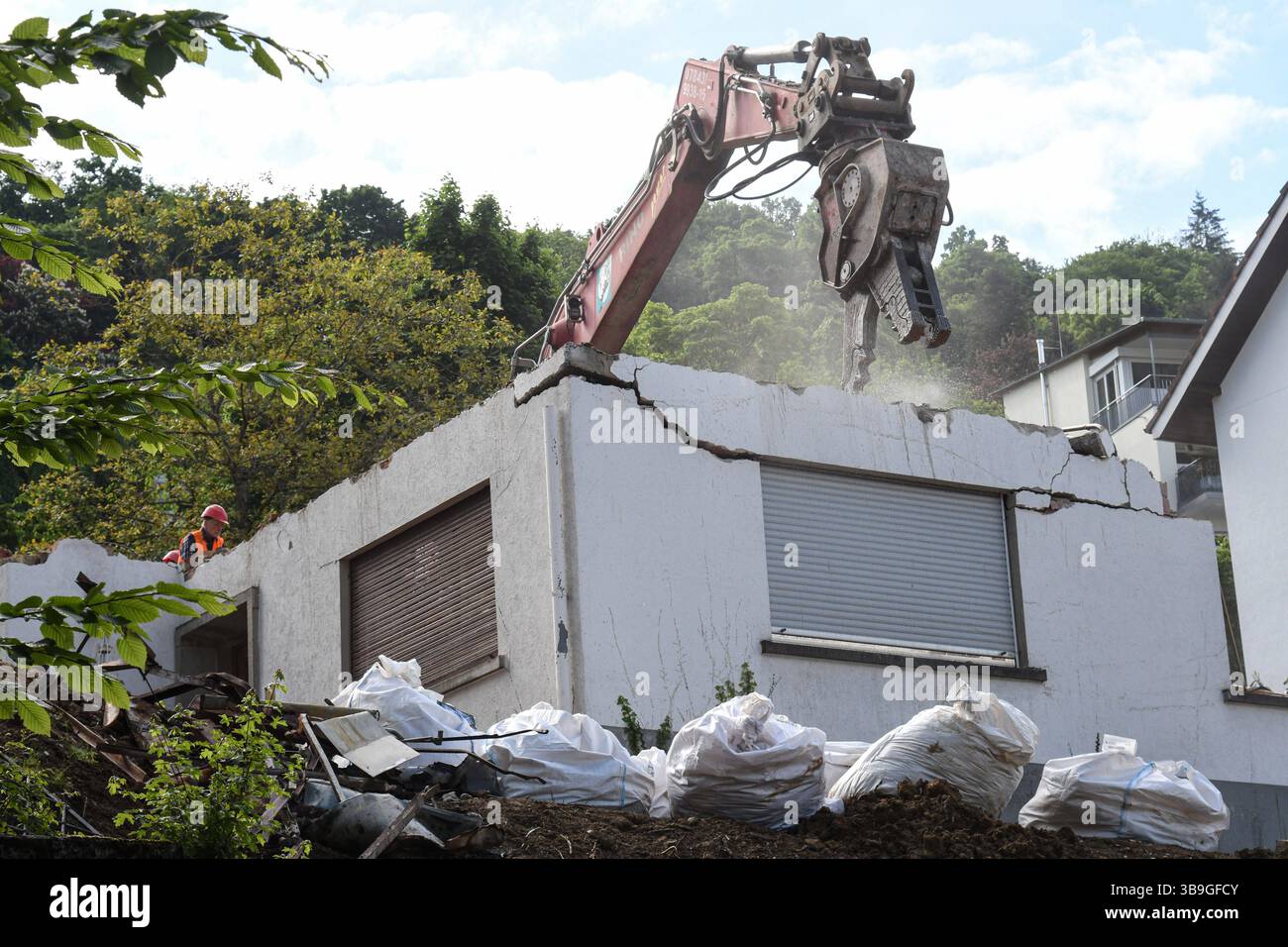 Ein Bagger zertruemmert ein Haus aus den 70iger Jahren in einem noblen ...