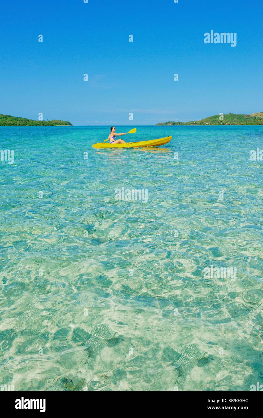 Woman sea kayaking in Fiji islands turquoise water, Waya island, Yasawa islands, Fiji Stock Photo