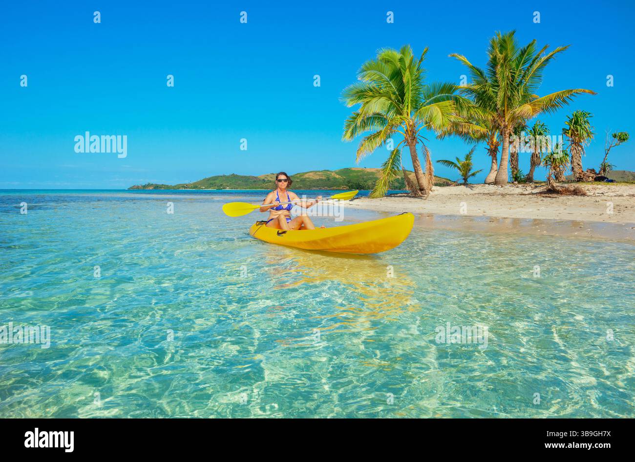 Woman sea kayaking in Fiji islands turquoise water, Waya island, Yasawa islands, Fiji Stock Photo