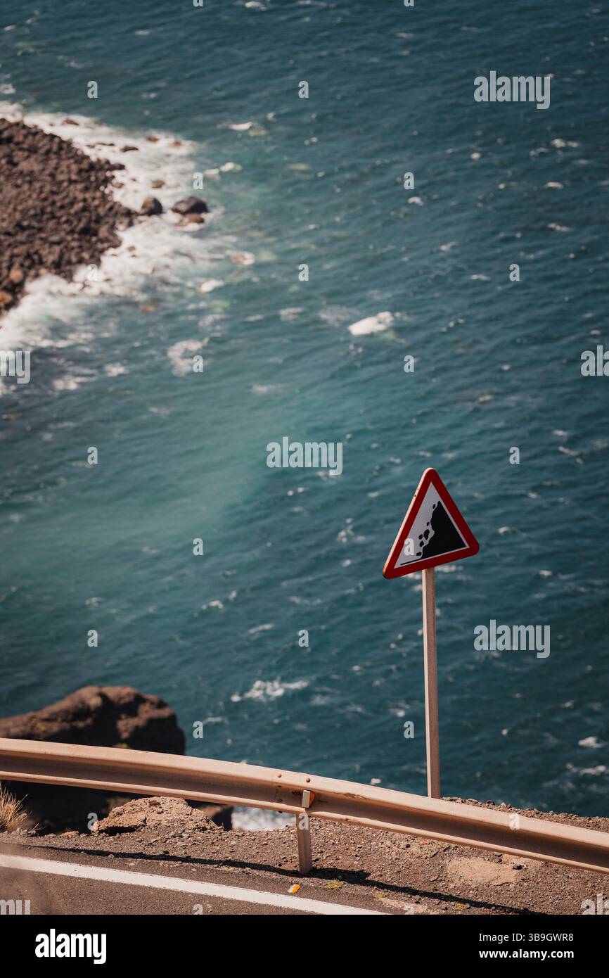 A sign warning of falling rocks stands on a coastal road on Gran ...
