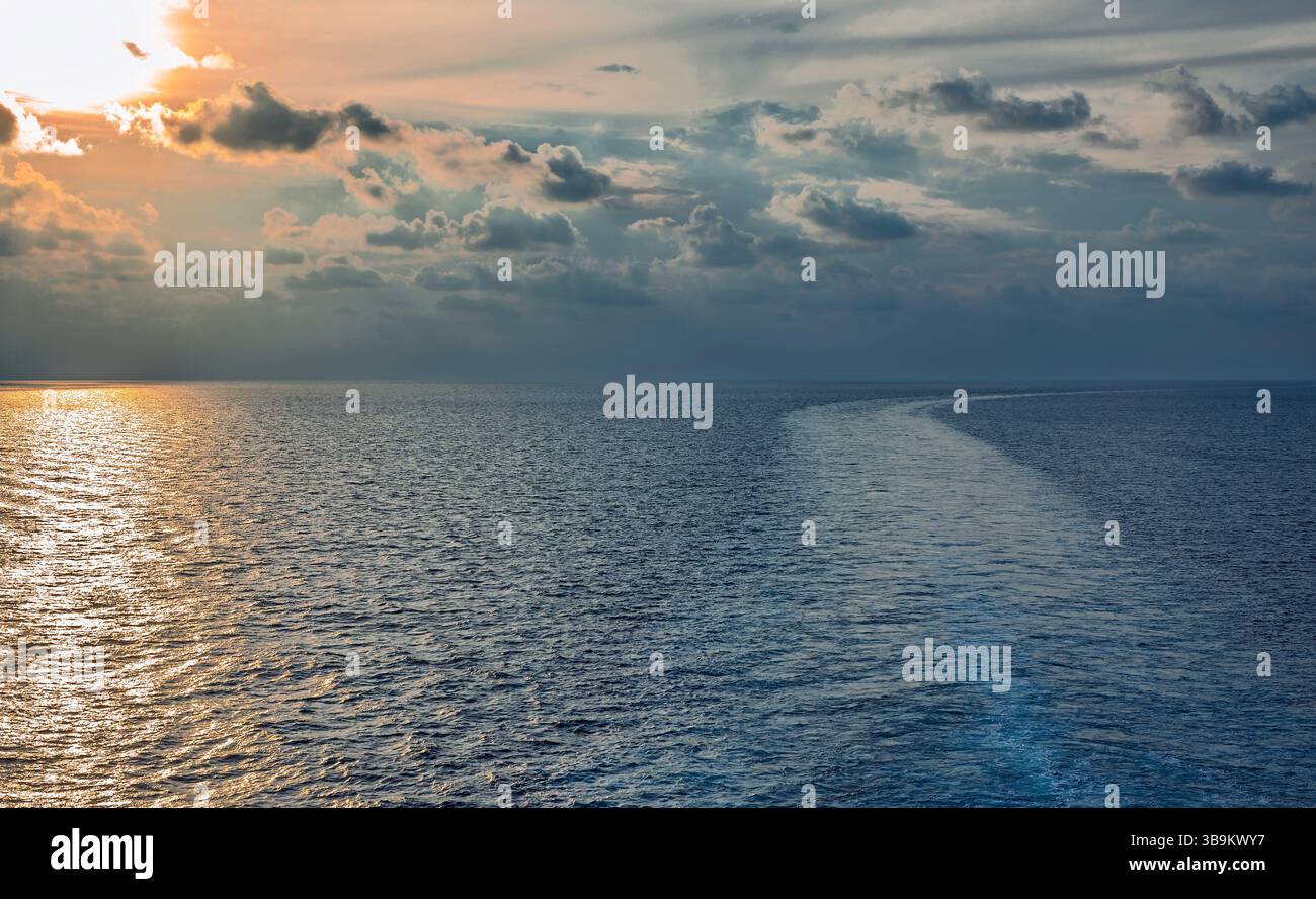 Golden light on the ocean at sunset or sunrise. View from a vessel ...