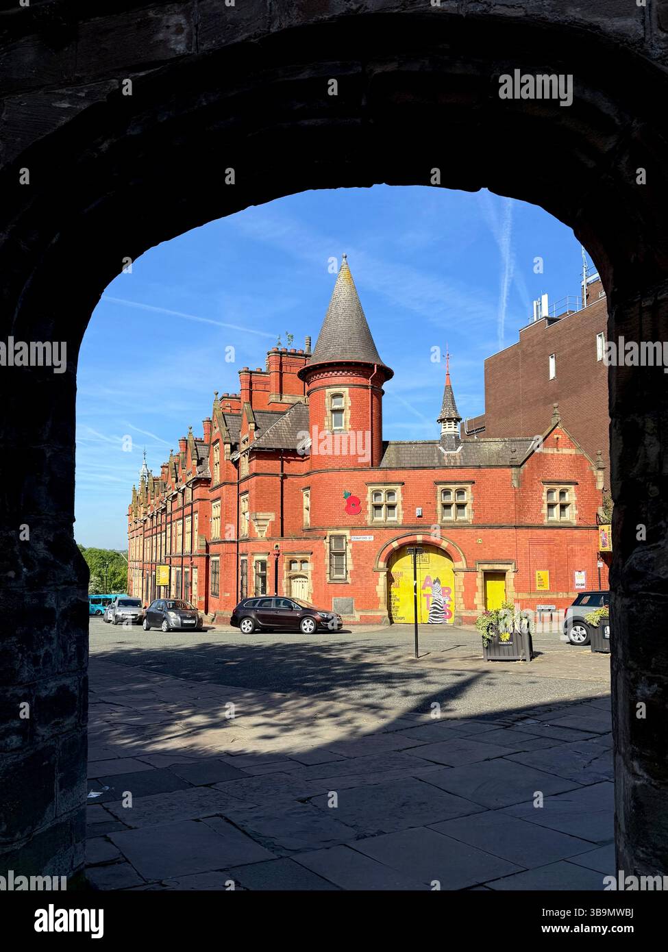Row of red brick buildings on Crawford Street, Wigan framed by archway ( entrance to All Saints parish church) - Smartphone Captured Stock Image