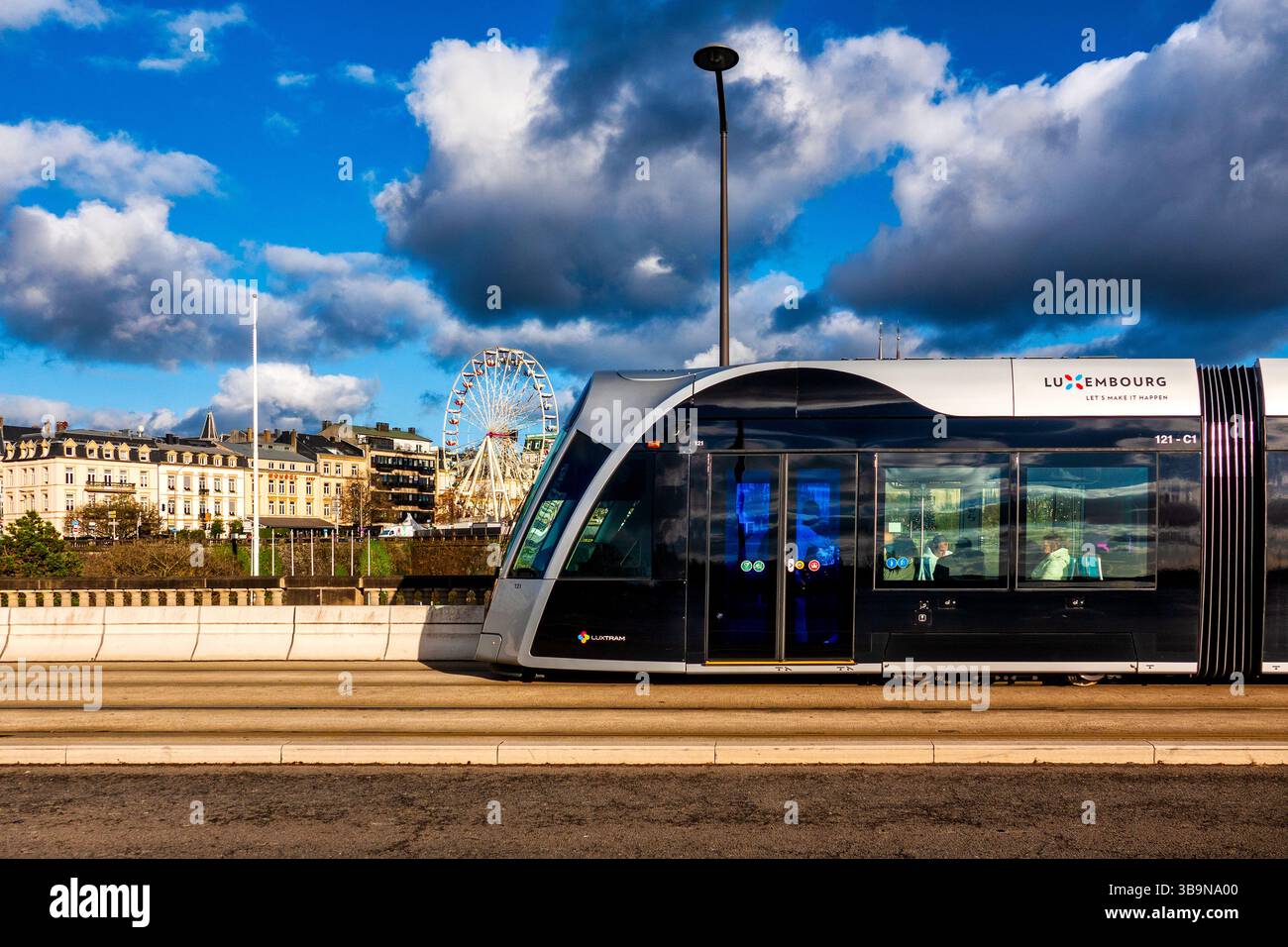 A CAF Urbos100 tram traverses the historic Adolphe Bridge (Pont Adolphe) in Luxembourg City, Luxembourg Stock Photo