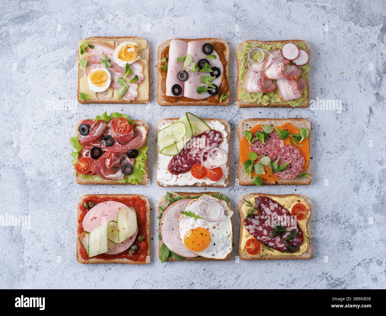 Set of eight different sandwiches with meat in square shape. Top view or flat lay. Assortment meat toasts on gray cement background. Idea, creative co Stock Photo