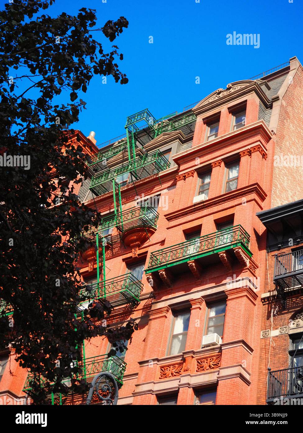 Red brick building with green fire escape in Brooklyn, New York Stock Photo
