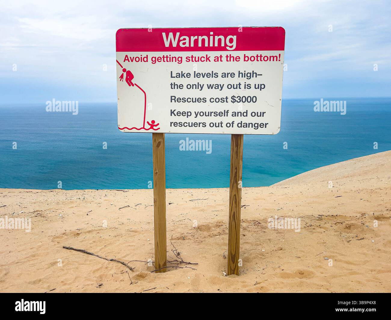Close-up photo of a posted warning sign at Sleeping Bear Dunes National Lakeshore advising hikers and visitors of costly rescue fees for getting stuck Stock Photo