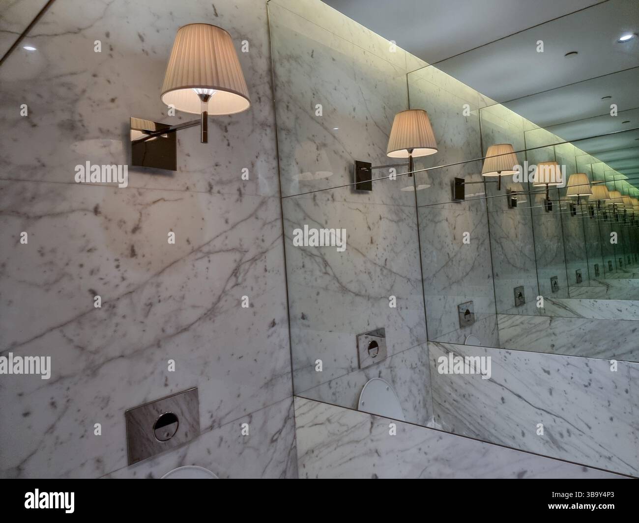 Infinite number of lamps on a marble wall, due to endless reflection of lamp shade in mirrors - Smartphone Captured Stock Image