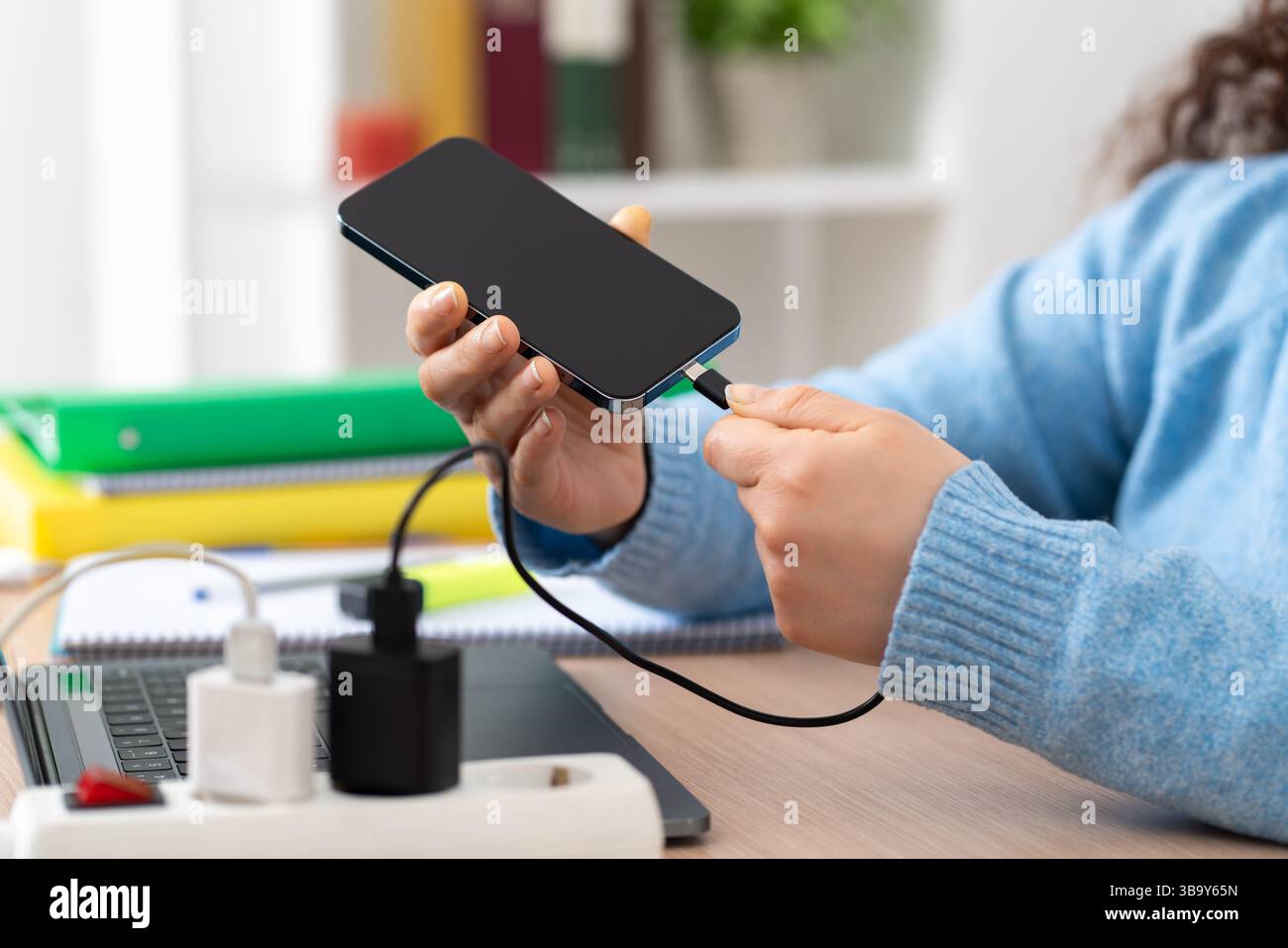 Close up of a business woman hand plugging charger cable to a smart phone at home Stock Photo