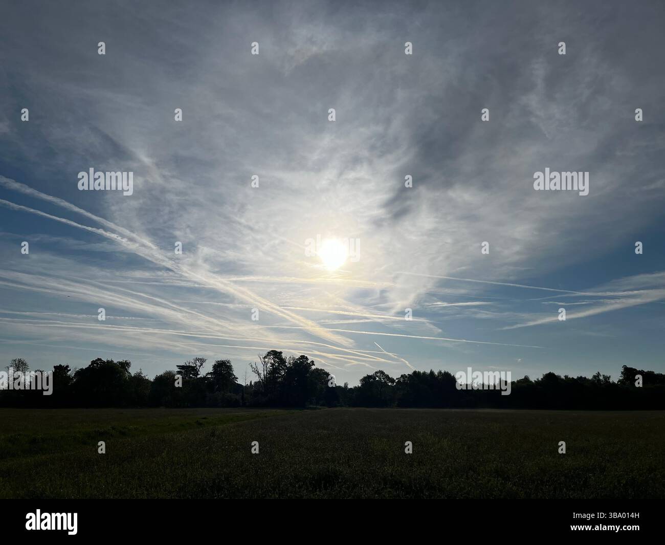 Busy sky above a field in the Cotswolds, soft cloud formation surrounding the sun. - Smartphone Captured Stock Image