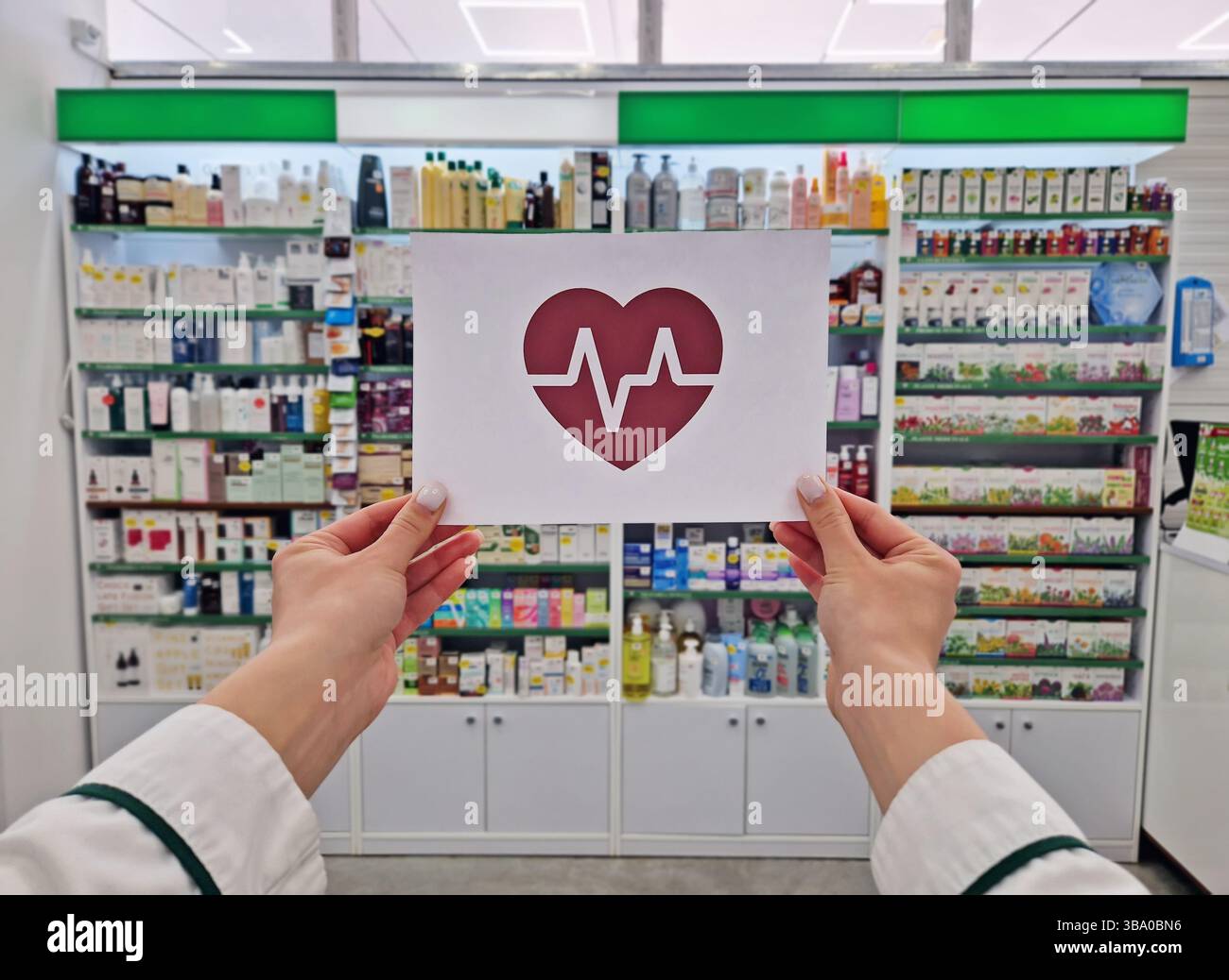 Female pharmacist hands holding a paper with a heart symbol and an electrocardiogram inside. Human healthcare and wellbeing concept. Health insurance - Smartphone Captured Stock Image