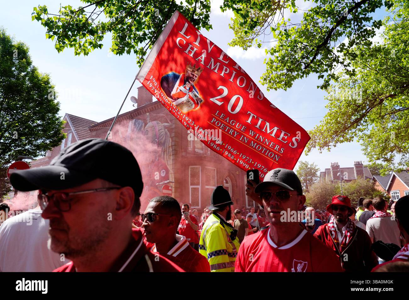 Liverpool fans gather and wave a flag as they await the arrival of the ...