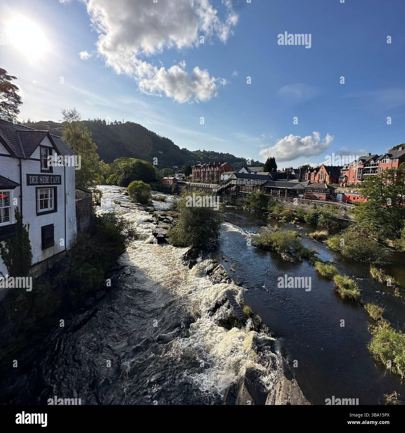 Sunny day view of the River Dee in Llangollen, Denbighshire, Wales, seen from the town bridge with trees and riverside buildings in the background. - Smartphone Captured Stock Image Sunny day view of the River Dee in Llangollen, Denbighshire, Wales, seen from the town bridge with trees and riverside buildings in the background. - Smartphone Captured Stock Image