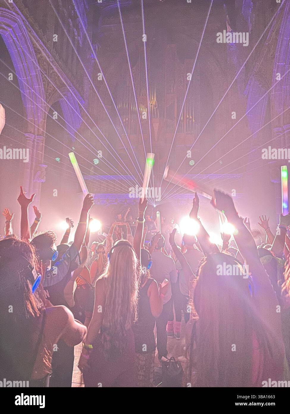 Silent Disco inside Manchester Cathedral with neon lights and dancing crowd, 18 August 2023. People wearing headphones and waving glowsticks. - Smartphone Captured Stock Image
