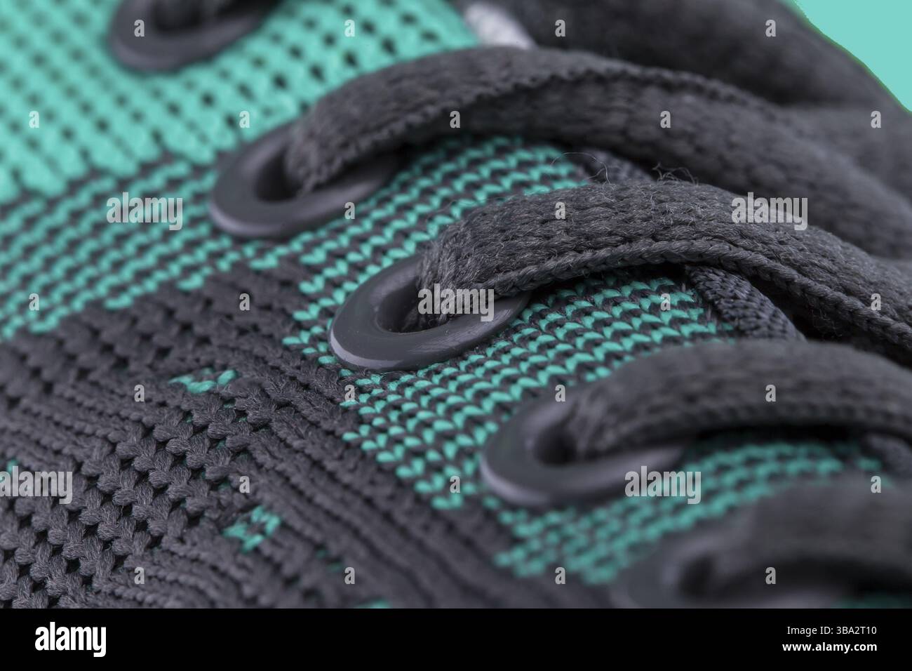 A fragment of a green sneaker with black laces close up. Sneaker texture Stock Photo