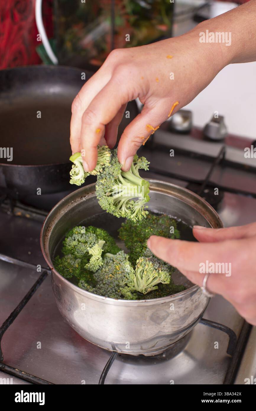 Hands throwing broccoli into boiling water Stock Photo - Alamy