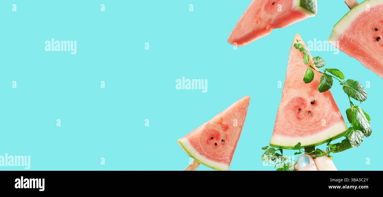 Juicy watermelon slices as popsicles on sticks with mint leaves on background, summer banner with summer refreshing treat Stock Photo