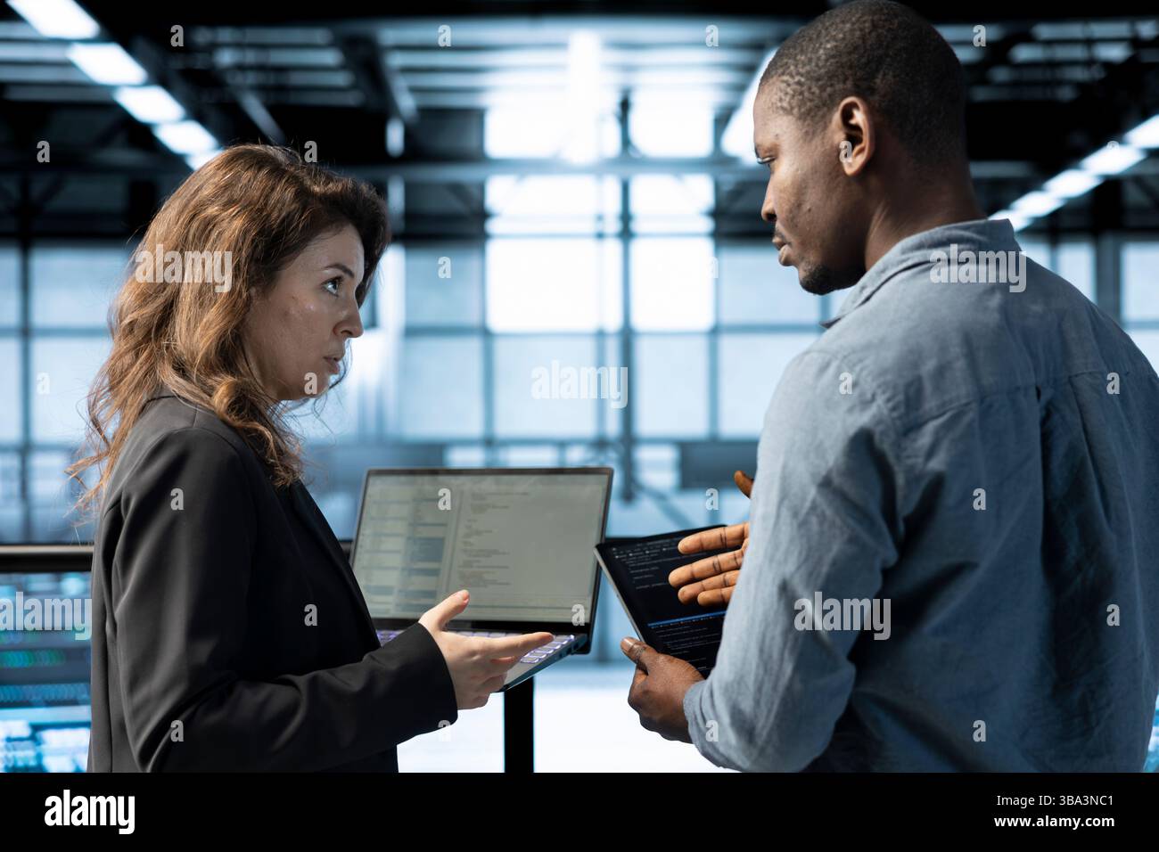 Engineers in data center using devices, employing machine learning models, analyzing historical usage patterns, predicting future infrastructure needs, allocating resources efficiently Stock Photo