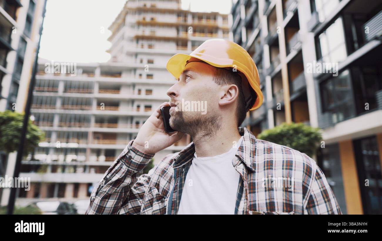 Engineer talking on phone. Architect using phone on construction site. Foreman phone call control process. Construction worker communications in const Stock Photo