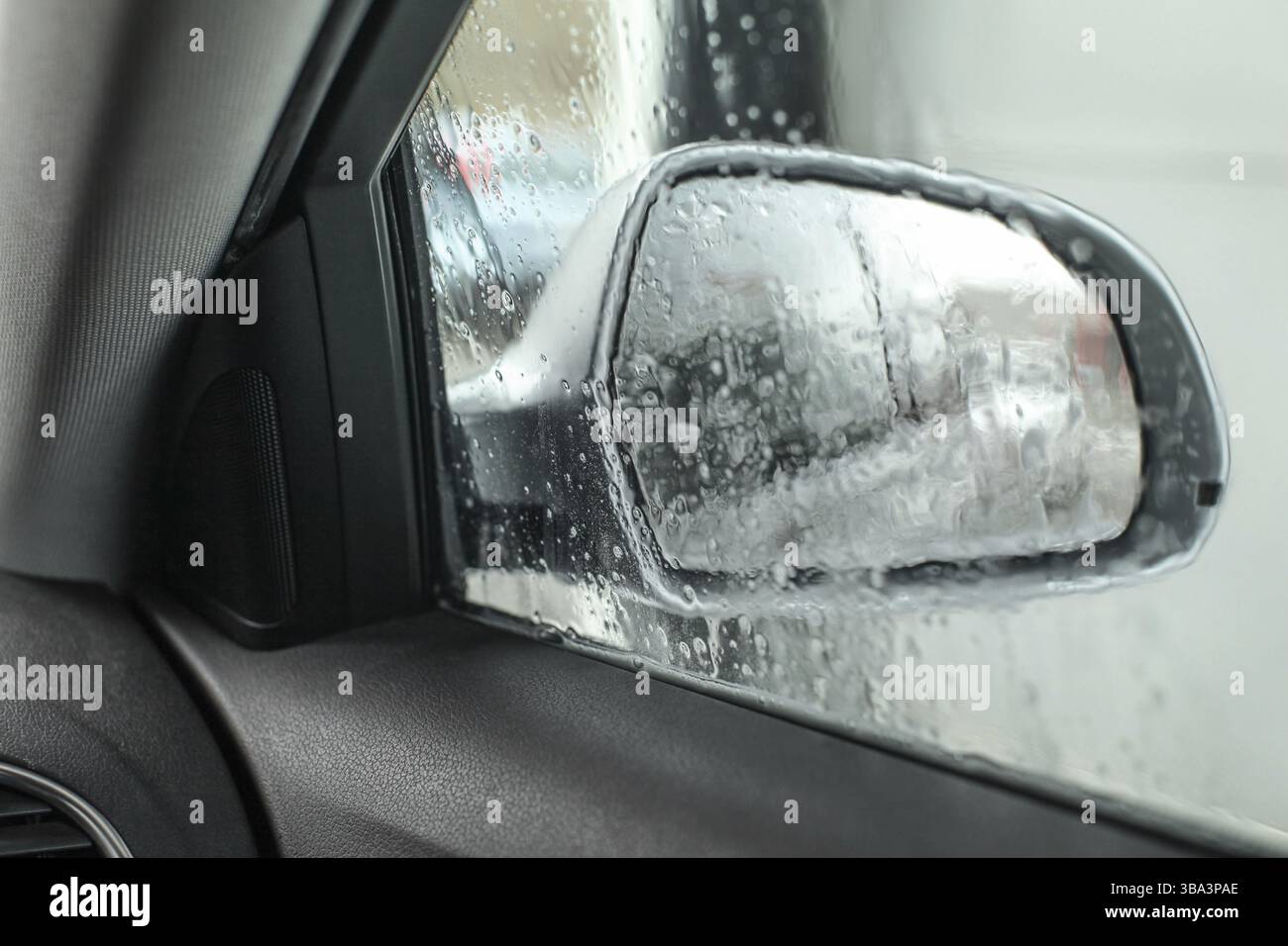 View from inside the car, looking at side mirror, wet from water and soap when being washed in carwash Stock Photo