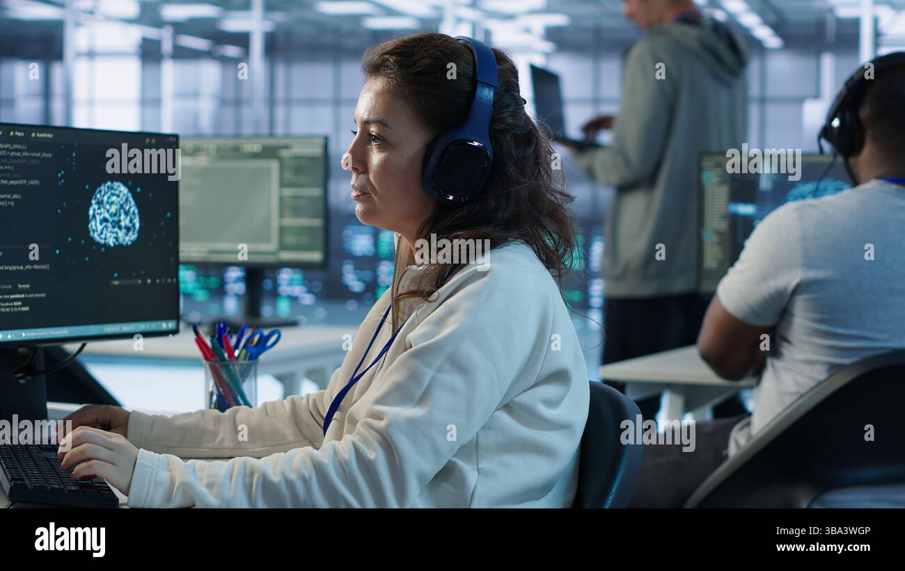 Developer listening music while programming in AI data center used for machine learning training. IT specialist wearing headphones running code to upgrade artificial intelligence tech, camera A Stock Photo