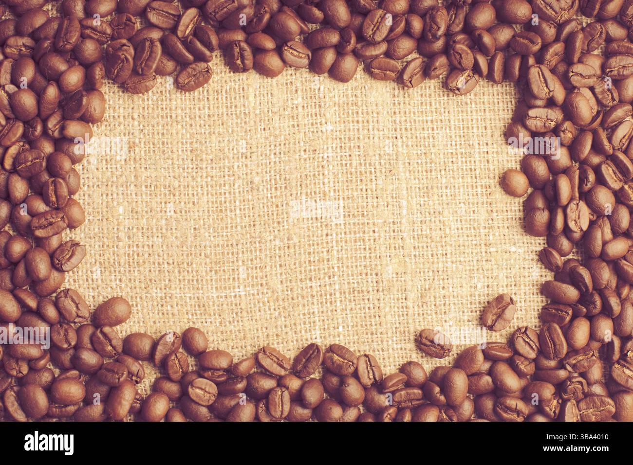 Spilled coffee beans frame over burlap textile Stock Photo