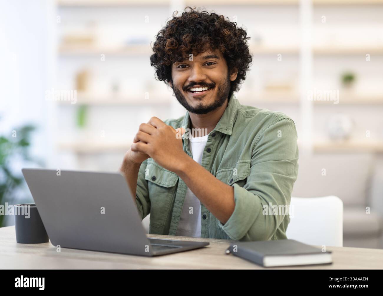 Cheerful indian guy programmer posing at workdesk Stock Photo