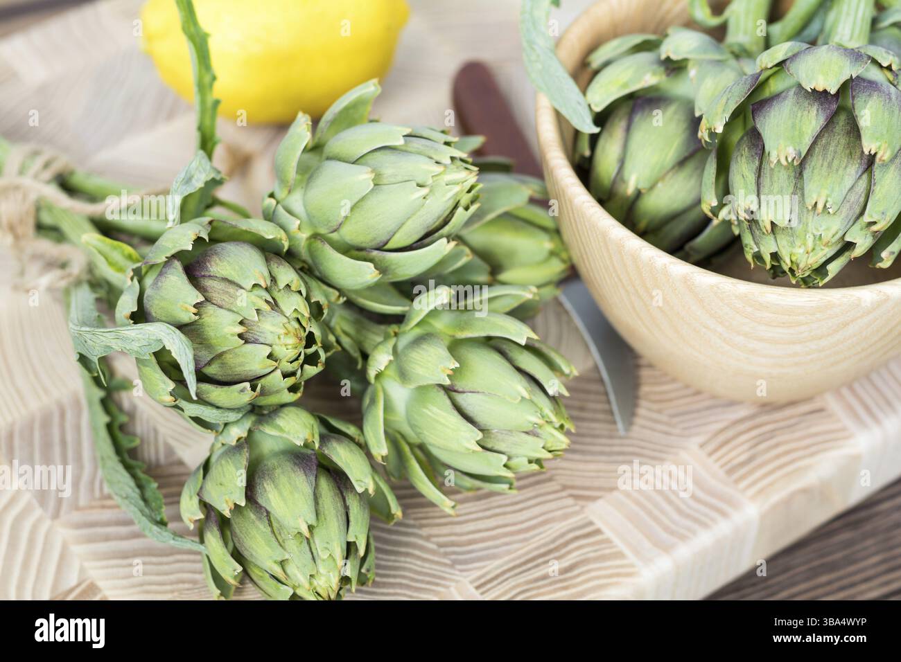 Two artichoke bouquets on kitchen table among some kitchen items. Top view Stock Photo