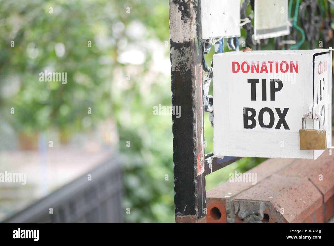 Donation tip box located in a community area with greenery Stock Photo