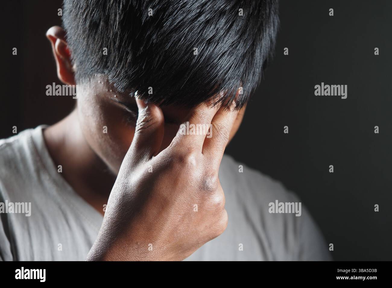Frustrated young man expressing emotions in low light setting Stock Photo