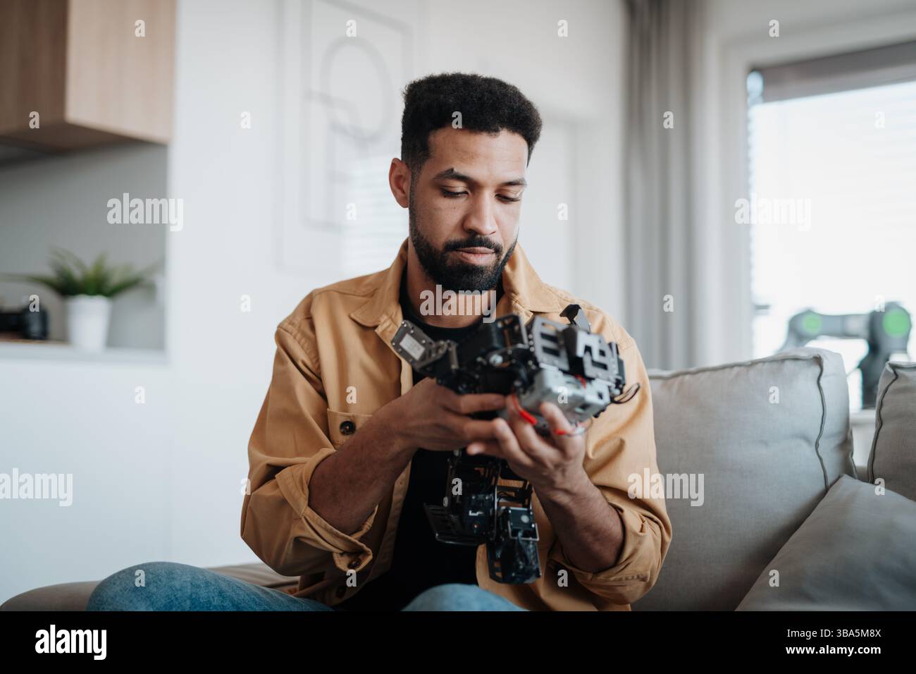 Handsome engineer student working on robot project at home. Stock Photo