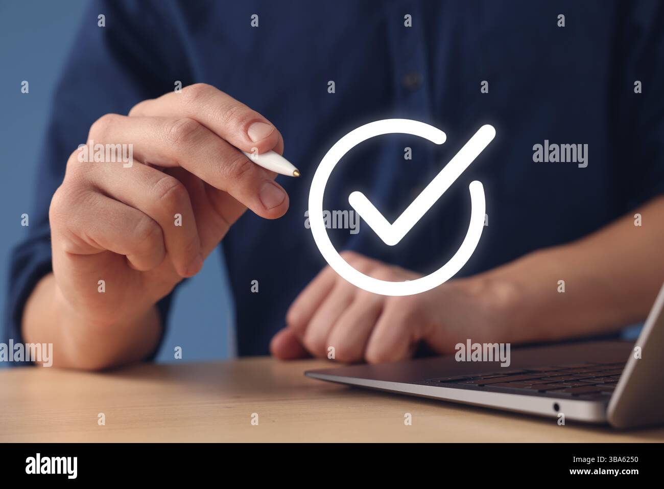 Approved. Man using laptop and touching virtual screen with check mark at table, closeup Stock Photo