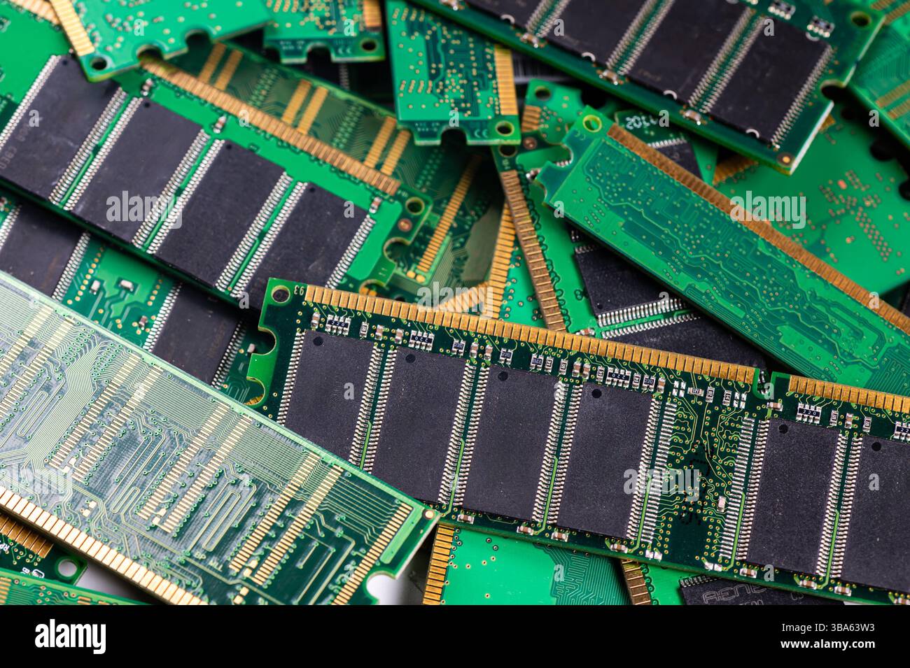 Various computer memory modules are piled on a green circuit board, showcasing technology. Stock Photo