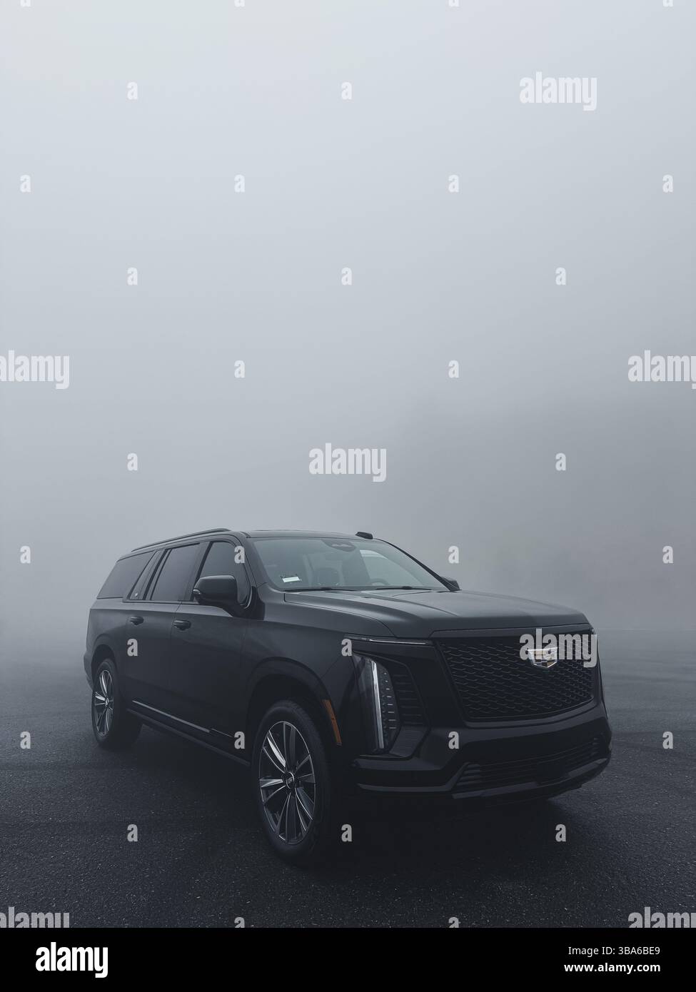 All-black Cadillac Escalade in heavy fog with dramatic lighting Stock Photo