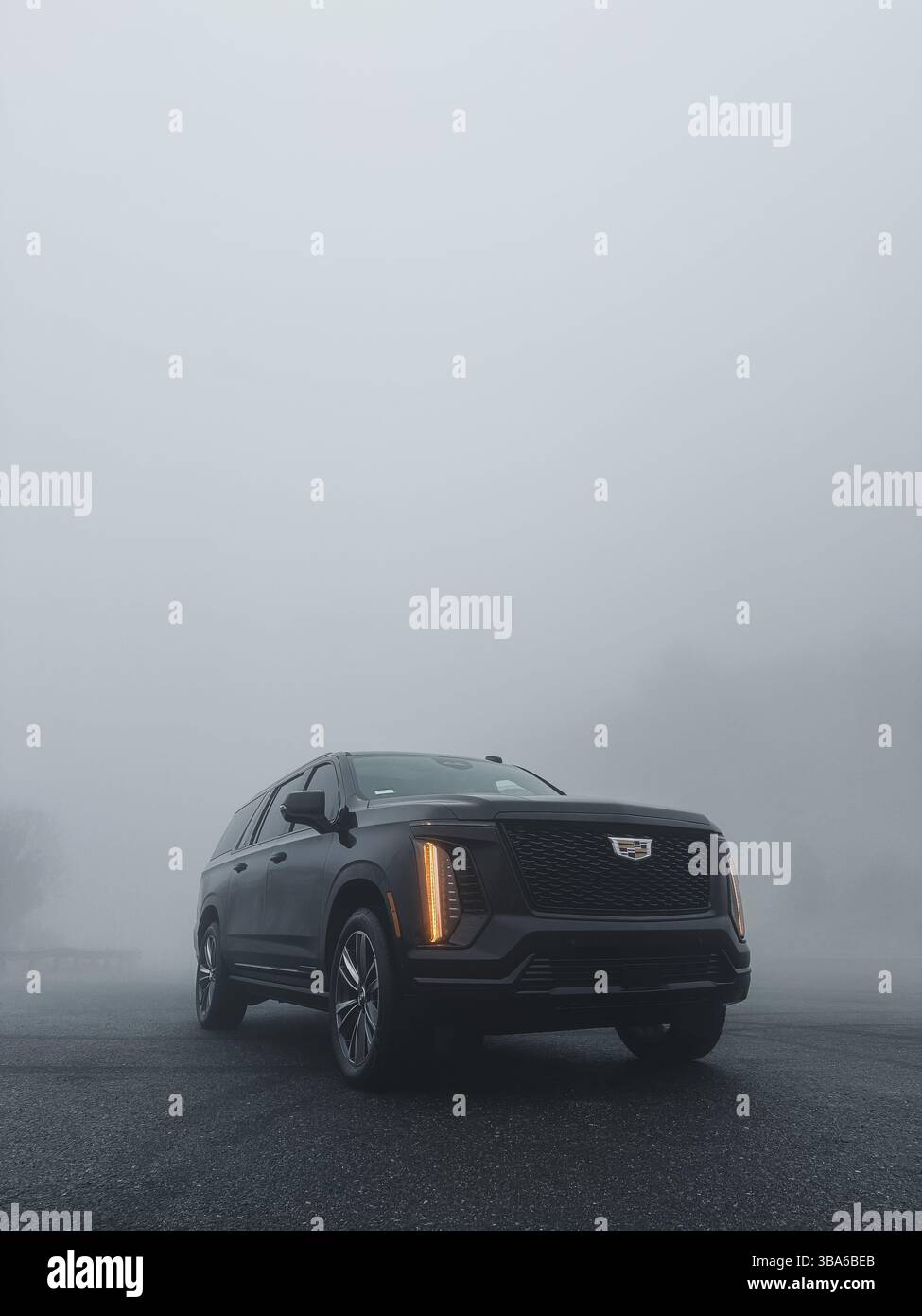All-black Cadillac Escalade in heavy fog with dramatic lighting Stock Photo